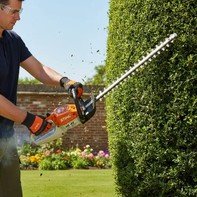 A person using a Stihl HS 45 gas hedge trimmer to trim a dense green hedge in a garden setting, viewed from a slight low angle with bright natural light, realistic style.